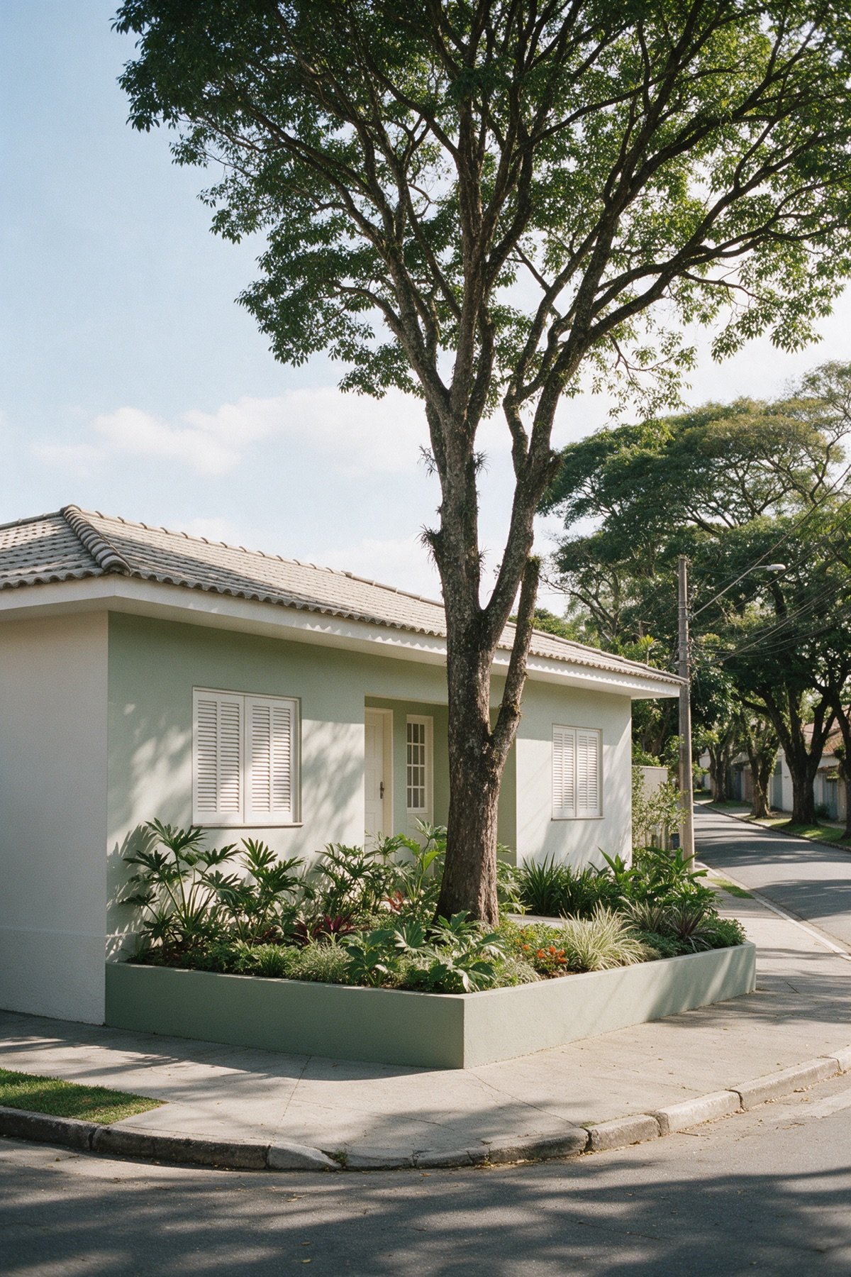 Fachada de casa térrea dos Jardins vista da calçada, com recuo ajardinado, árvore alta na frente e rua arborizada ao lado Fachada de casa térrea dos Jardins vista da calçada, com recuo ajardinado, árvore alta na frente e rua arborizada ao lado