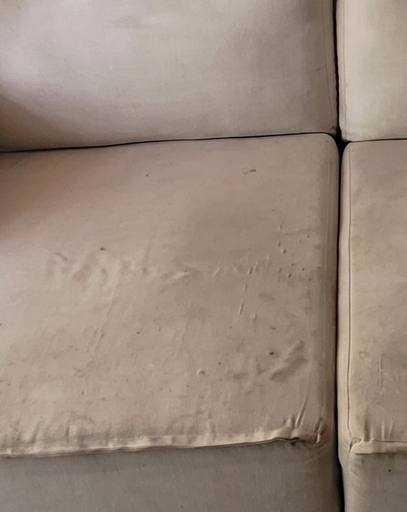 Sofá de tecido claro com o assento encardido, antes da higienização
