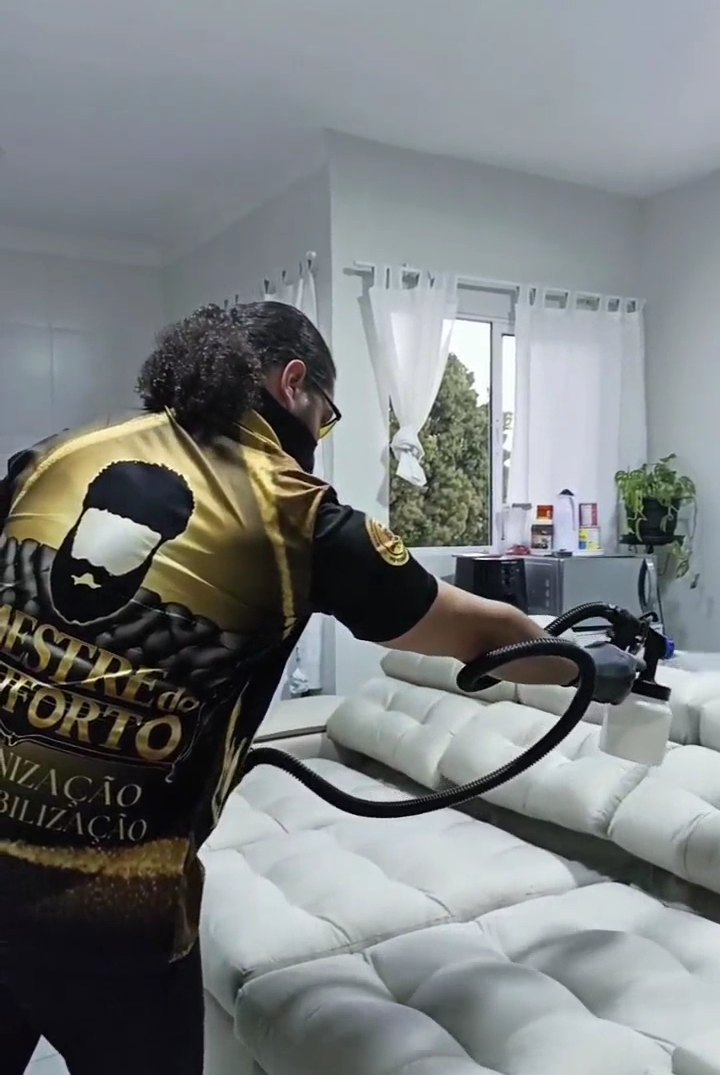 Técnico uniformizado da Herbo Clean higienizando um sofá na casa do cliente Técnico uniformizado da Herbo Clean higienizando um sofá na casa do cliente